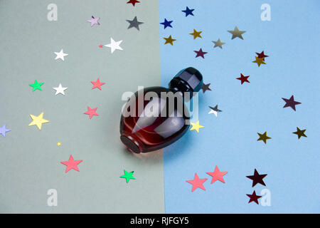 Flacon de parfum et le scintillement des étoiles sur fond bleu et vert Banque D'Images