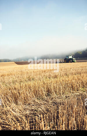 Champ de chaumes, le tracteur sur arrière-plan Banque D'Images