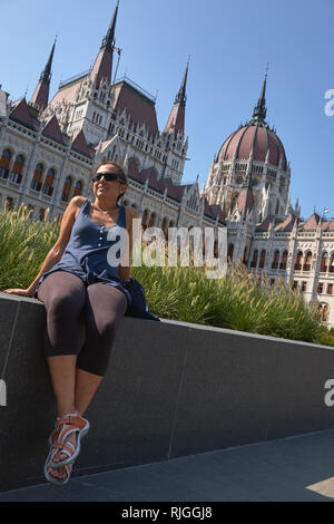 Belle jeune femme espagnole assis devant le Parlement hongrois à Budapest, dans la capitale de la Hongrie. Banque D'Images