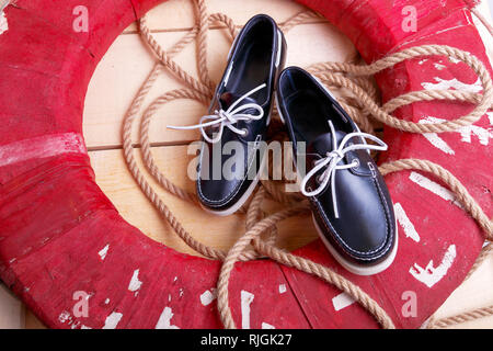 Chaussures bateau bleu sur fond de bois près de bouée de rouge et de la corde. Vue d'en haut. Banque D'Images