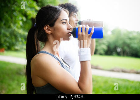 Couple boit de l'eau après la course pour refaire le plein d'énergie et d'hydrater Banque D'Images