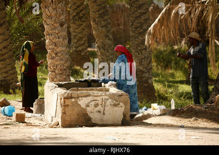 Femmes avec une blanchisserie au puits de Douz oasis Banque D'Images