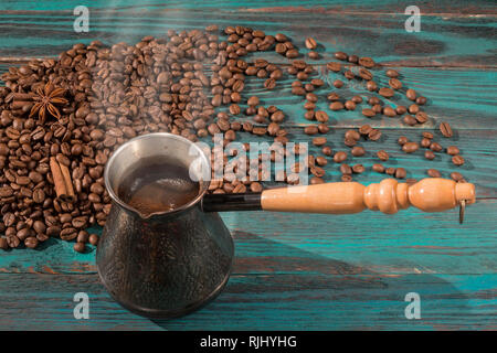 Du café fraîchement moulu dans le cezve (jezve) dispersés et de café torréfié, de cannelle et d'anis étoilé sur la table en bois turquoise Banque D'Images