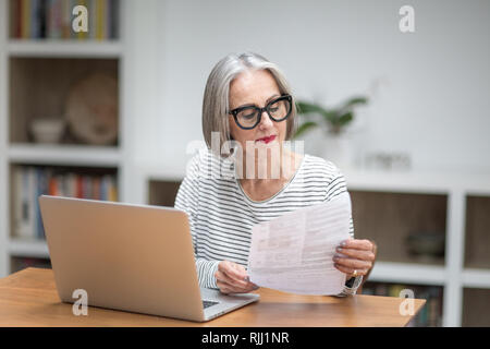 Femelle adulte mature payer facture en ligne à l'aide d'un ordinateur portable Banque D'Images