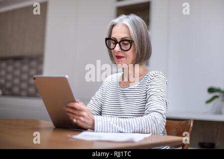 Femelle adulte mature payer facture en ligne à l'aide d'une tablette numérique Banque D'Images