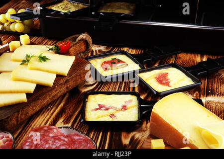 Délicieux fromage à raclette fondue suisse traditionnel servi dans des poêlons au salami Banque D'Images
