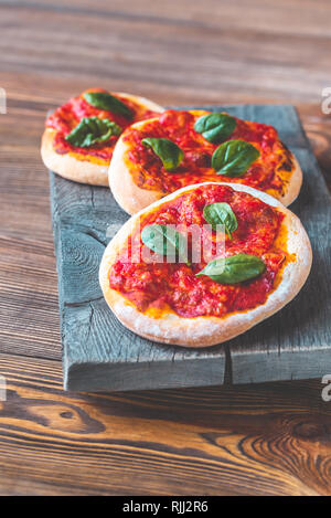 Mini pizzas Margherita avec fromage rouge sur la planche de bois Banque D'Images