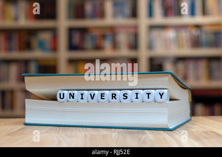 Dés dans une forme de livre le mot "éducation". Livre est allongé sur une table en bois dans une bibliothèque. Banque D'Images