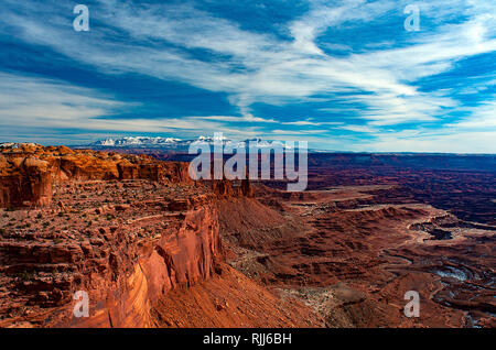 Janvier 2019 : les murs du canyon de grès rouge de l'île dans le ciel vers les sommets enneigés de la chaîne de Montagnes La Sal, Canyonlands NP. Banque D'Images