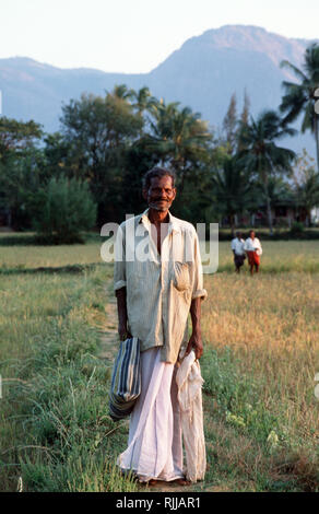 Un homme du village, marche à pied à la maison après une longue journée à travailler dans les champs de riz dans un petit village près de Palakkad. Une luxuriante et fertile, l'Inde du sud maintai Banque D'Images