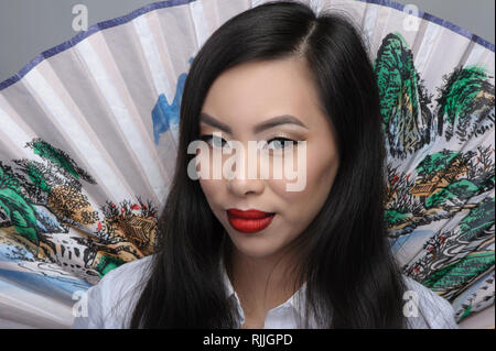 Portrait of beautiful young asian woman avec ventilateur sur l'arrière-plan Banque D'Images