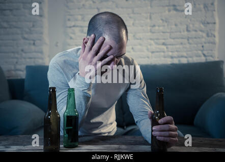 Les jeunes hommes ivres triste de boire une bière et d'alcool se sentir perdu, seul et désespéré dans la douleur et le stress émotionnel. Les gens et l'abus d'alcool, la toxicomanie un Banque D'Images