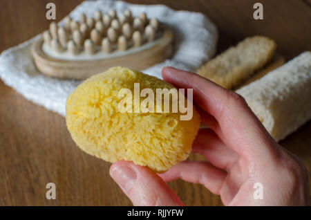 Set de bain naturel naturel. éponge de mer dans la main de femme contre eco en plastique naturel de luffa, brosses en bois, serviette de vie durable. Banque D'Images