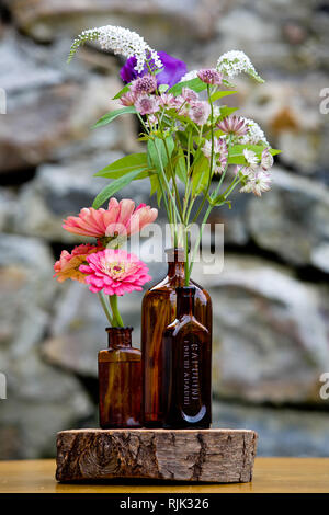 Légende - arrangement de fleurs de mariage série. Bouquet de fleurs pour un mariage à l'événement dans des bouteilles soufflées sur bois Banque D'Images