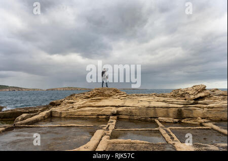 Sac à dos avec l'homme debout sur le dessus de la pierre calcaire salines donnant sur la mer de nuages de pluie orageuse dans la distance Banque D'Images