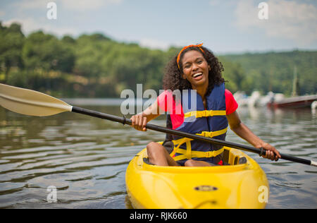 Portrait of a smiling young woman in yellow kayak. Banque D'Images