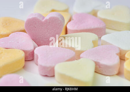 Couleur macro photo de candy hearts couché sur fond blanc, un cœur rose est debout, copy space Banque D'Images