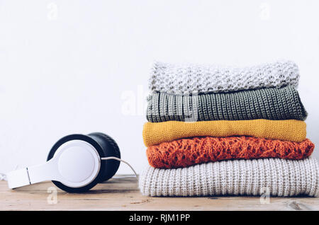 Pile de pulls en laine tricoté couleurs d'automne sur table en bois avec casque. Différents modèles de tricot avec des vêtements pliés en pile. Confortable chaud wint Banque D'Images