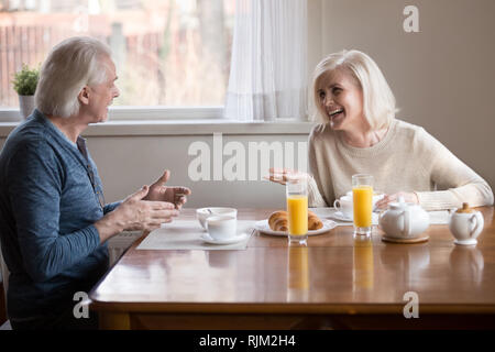 Vieux couple s'amusant rire assis manger le petit déjeuner dans la cuisine Banque D'Images