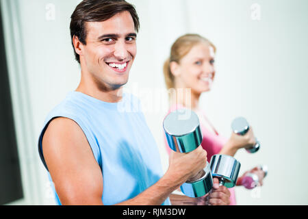 Couple exercising in gym, à l'aide de poids Banque D'Images