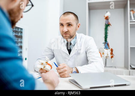 Portrait d'un thérapeute principal pendant la consultation médicale modèle anatomique montrant des vertèbres dans le bureau Banque D'Images