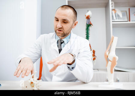 Portrait d'un thérapeute principal pendant la consultation médicale modèle anatomique montrant des vertèbres dans le bureau Banque D'Images