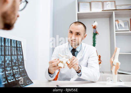 Portrait d'un thérapeute principal pendant la consultation médicale modèle anatomique montrant des vertèbres dans le bureau Banque D'Images