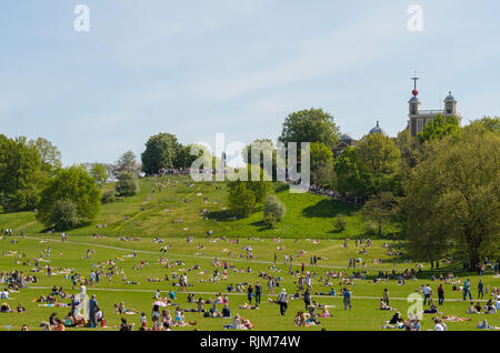 Des foules de gens se coucher sur l'herbe et profiter du soleil et de la chaleur pendant une vague dans le parc de Greenwich, Londres, Angleterre. Banque D'Images