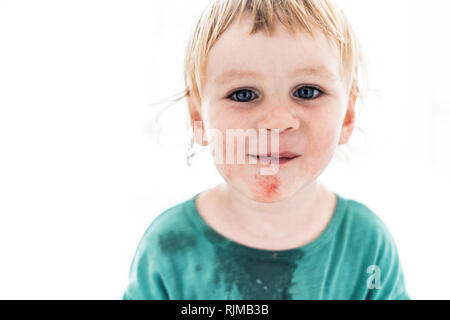 Un joli portrait artistique d'un jeune garçon souriant avec des yeux d'un bleu profond qui vient de manger la pastèque. Le tout-petit est à la droit dans la caméra. Banque D'Images