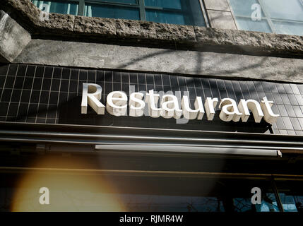 D'en bas photo de panneau blanc Restaurant accroché sur mur carrelé noir en plein soleil à Hambourg, Allemagne Europe Banque D'Images