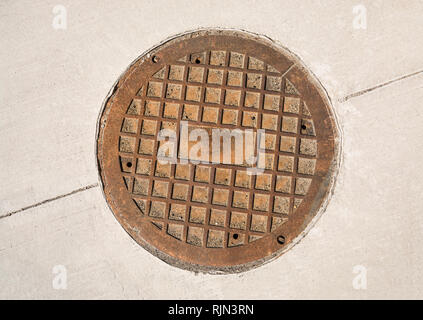 Manhole fonte éclosent sur le revêtement en béton. Banque D'Images