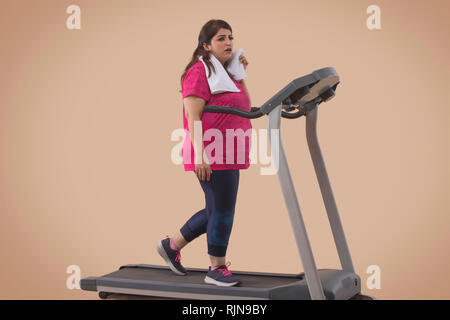 Grosse Femme Faire de l'exercice sur tapis roulant dans une salle de sport Banque D'Images