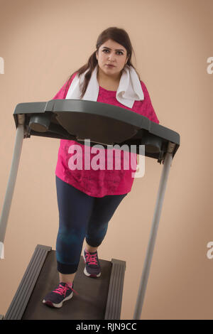 Grosse Femme Faire de l'exercice sur tapis roulant dans une salle de sport Banque D'Images