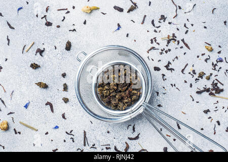 Les feuilles de thé pour le brassage dans une passoire sur un fond gris. Copy space Banque D'Images