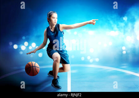 Belle femme asiatique en uniforme de basket-ball de dribbler le ballon sur un terrain de basket-ball Banque D'Images