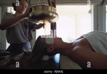 Légende : Udaipur, Rajasthan, Inde - mai 2003. Un thérapeute au Banyan Tree Spa de l'Oberoi Udaivilas resort du Shirodhara effectue sur un invité. Trio Banque D'Images