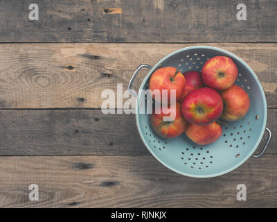 Delicious pommes biologiques dans une vieille passoire sur une table en bois rustique, style vintage ton plat avec vue de dessus Banque D'Images