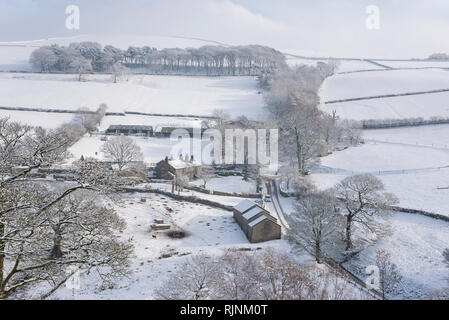 Ferme sur une colline près de fauche dans le Peak District, Derbyshire, Angleterre. Un beau matin d'hiver enneigé. Banque D'Images