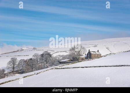 Maison sur les collines près de Hayfield, Derbyshire, Angleterre. Un beau matin neigeux dans le parc national de Peak District. Banque D'Images