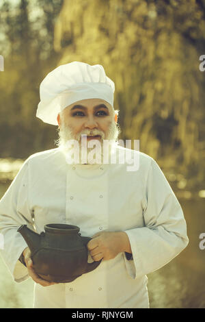 Cuisinier barbu avec fer à repasser plateau électrique Banque D'Images