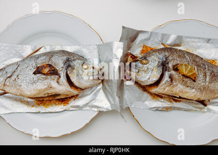 Deux la dorade poisson sur la feuille d'aluminium sur le tableau blanc - Vue de dessus de la nourriture délicieuse filtre vintage citron fait maison Banque D'Images