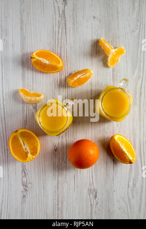 Jus d'orange dans des bocaux en verre blanc sur fond de bois, vue de dessus. Mise à plat, d'en haut, vue d'en haut. Banque D'Images