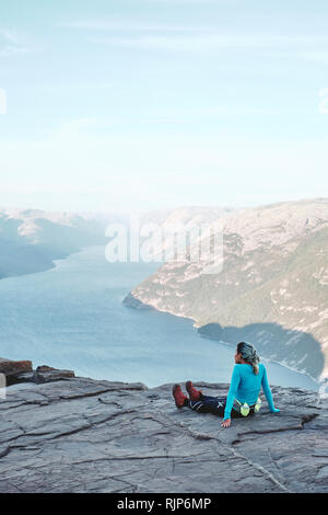 Une fille se repose et randonneur profitant de la vue sur le haut de l'Pulpit Rock / Prekestolen Preikestolen ou en Norvège Banque D'Images