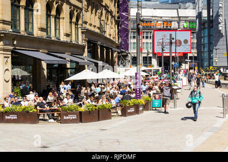 Une journée d'été dans le centre-ville de Manchester avec beaucoup de gens assis boire et manger à l'extérieur et Bar Banyan d'autres restaurants et bars du triangle, pour Banque D'Images