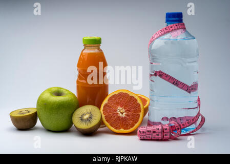 Remise en forme des femmes de la vie encore. L'alimentation saine, des fruits, les jus et l'eau sur fond gris. Centre sportif et de vie sain concept. Banque D'Images