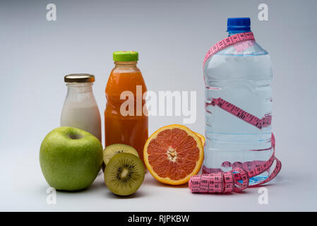 Remise en forme des femmes de la vie encore. L'alimentation saine, des fruits, les jus et l'eau sur fond gris. Centre sportif et de vie sain concept. Banque D'Images