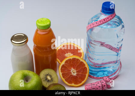 Remise en forme des femmes de la vie encore. L'alimentation saine, des fruits, les jus et l'eau sur fond gris. Centre sportif et de vie sain concept. Banque D'Images