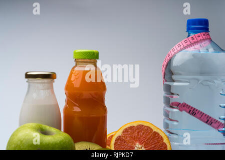 Remise en forme des femmes de la vie encore. L'alimentation saine, des fruits, les jus et l'eau sur fond gris. Centre sportif et de vie sain concept. Banque D'Images