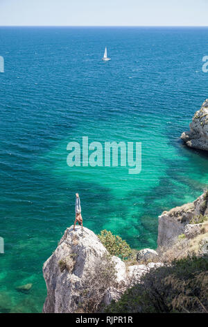 Young man doing handstand on coastal rock, Cagliari, Sardaigne, Italie Banque D'Images