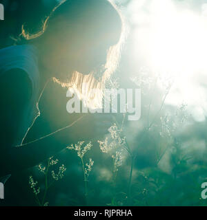 Woman smelling flowers in forest Banque D'Images